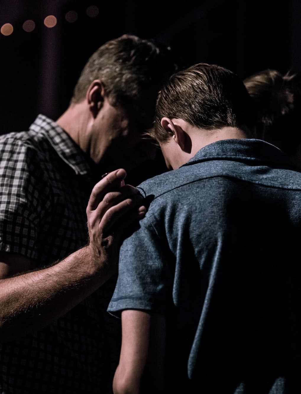 two men huddled together praying
