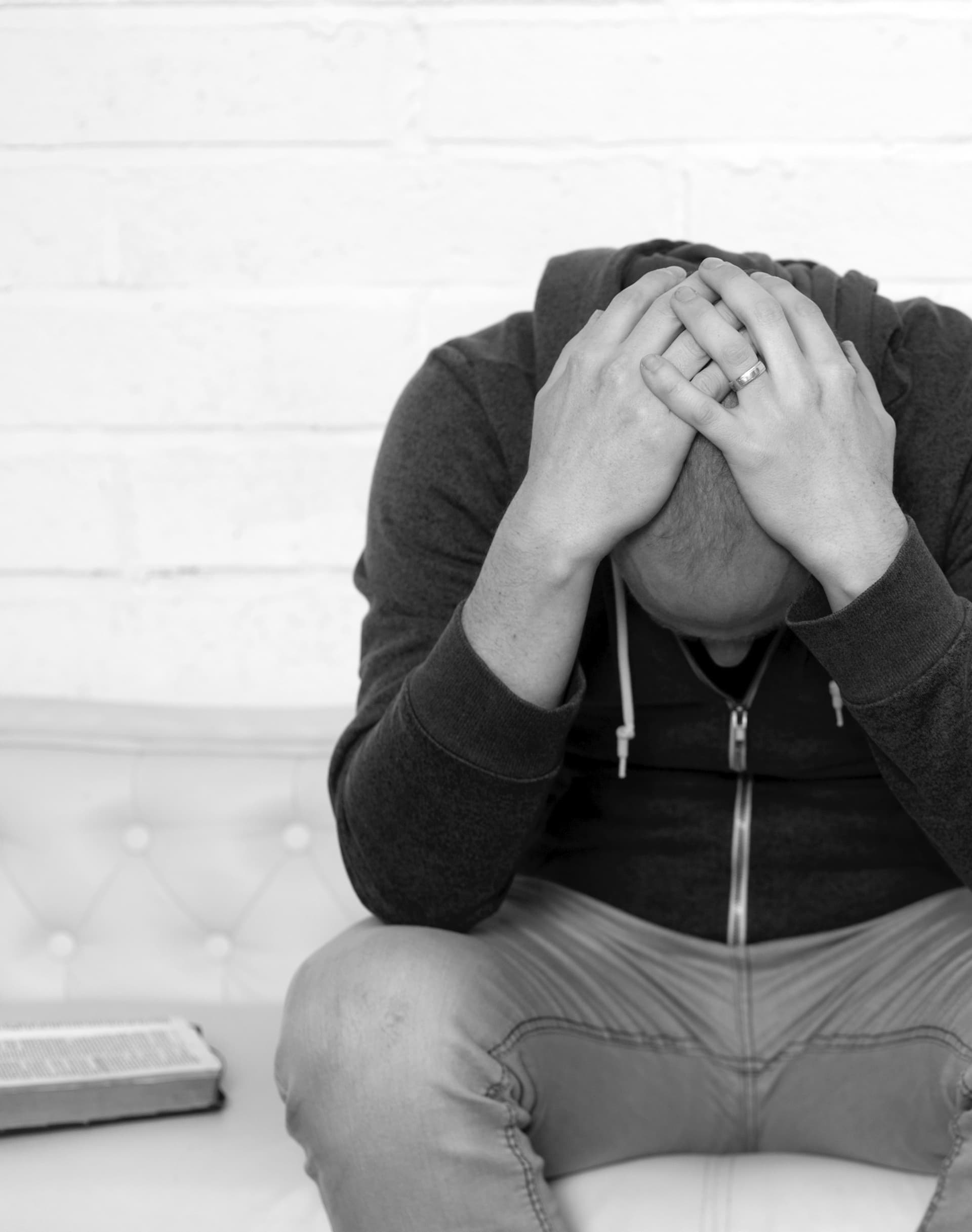 man sitting on a couch with his head in his hands