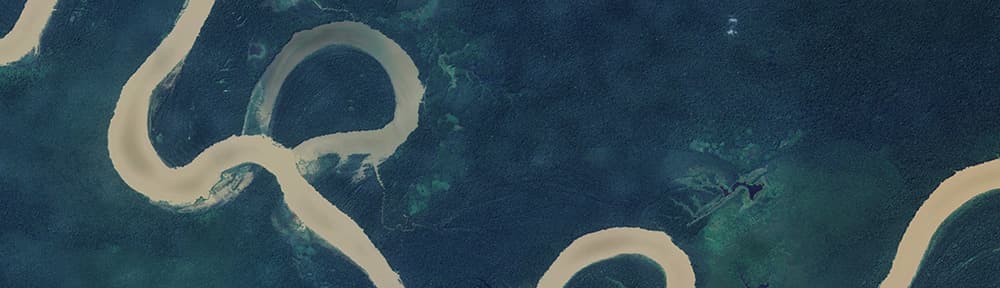 Aerial of twisting river through dark trees