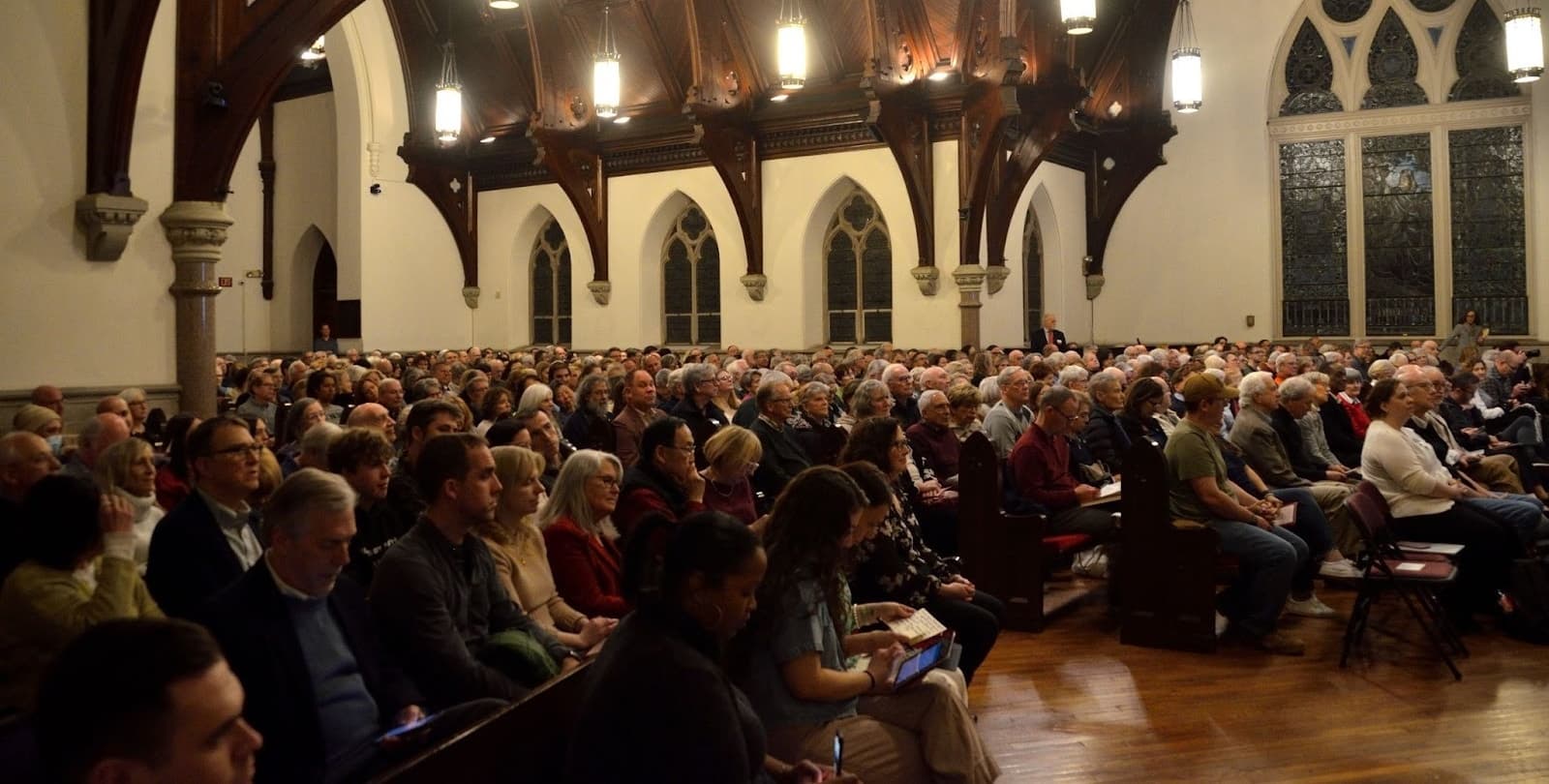 A large crowd sits in pews in a church at a BioLogos event.