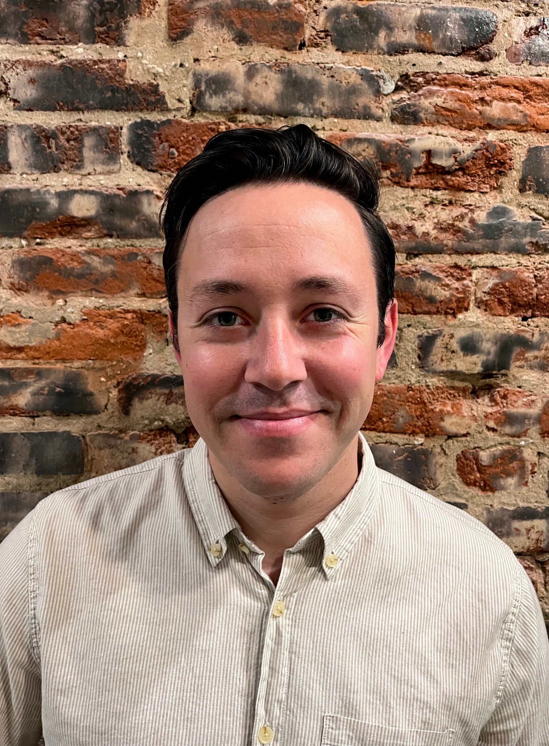 Headshot of Aaron Black. Aaron has black hair and is wearing a button-up shirt.
