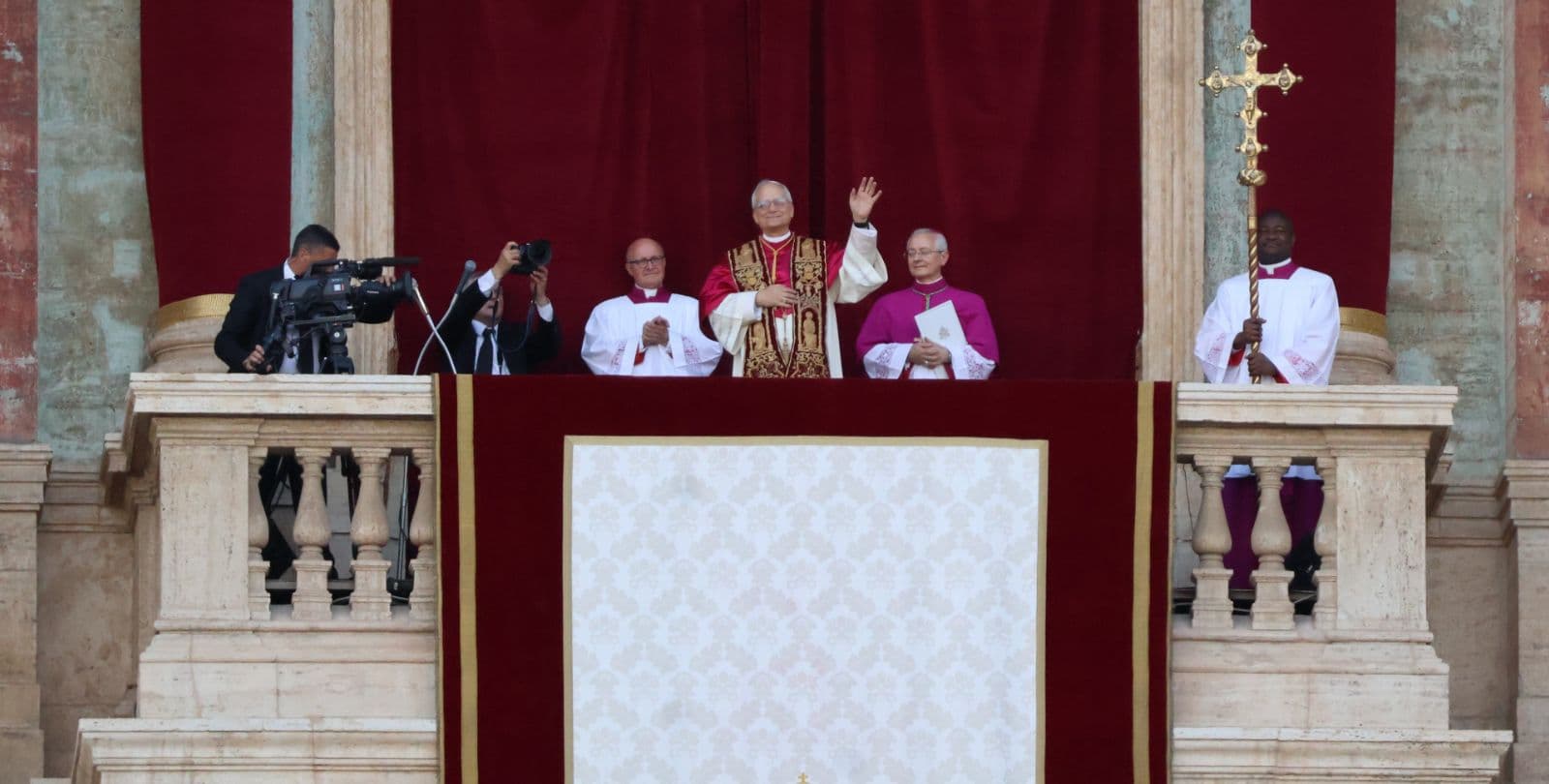 Pope Leo stands and waves on a balcony after his election as Pope.