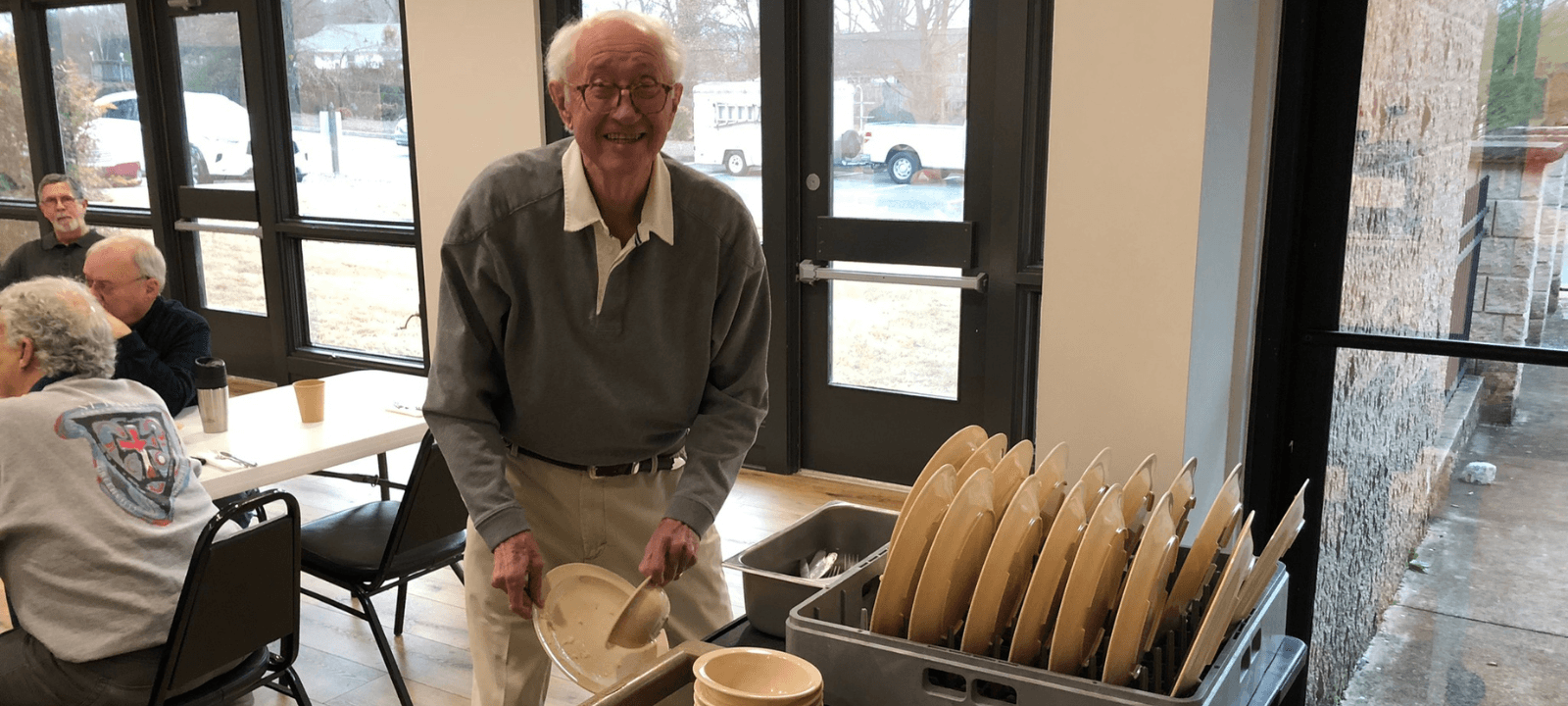 A man smiles at the camera as he scrapes his reusable plate.